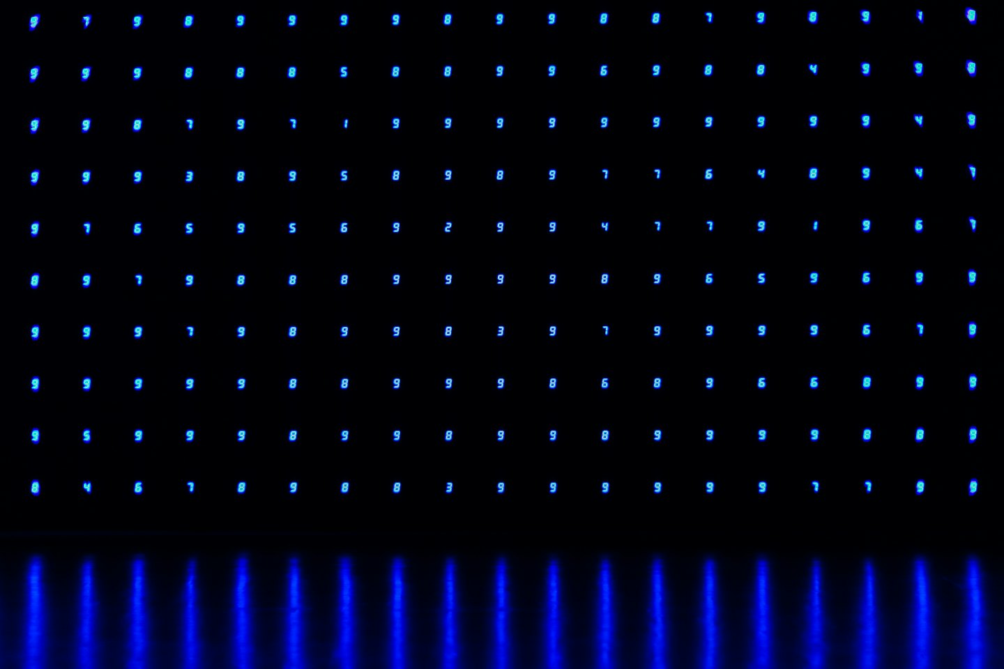 Abstrakter Raster aus leuchtend blauen digitalen Zahlen auf Schwarz.