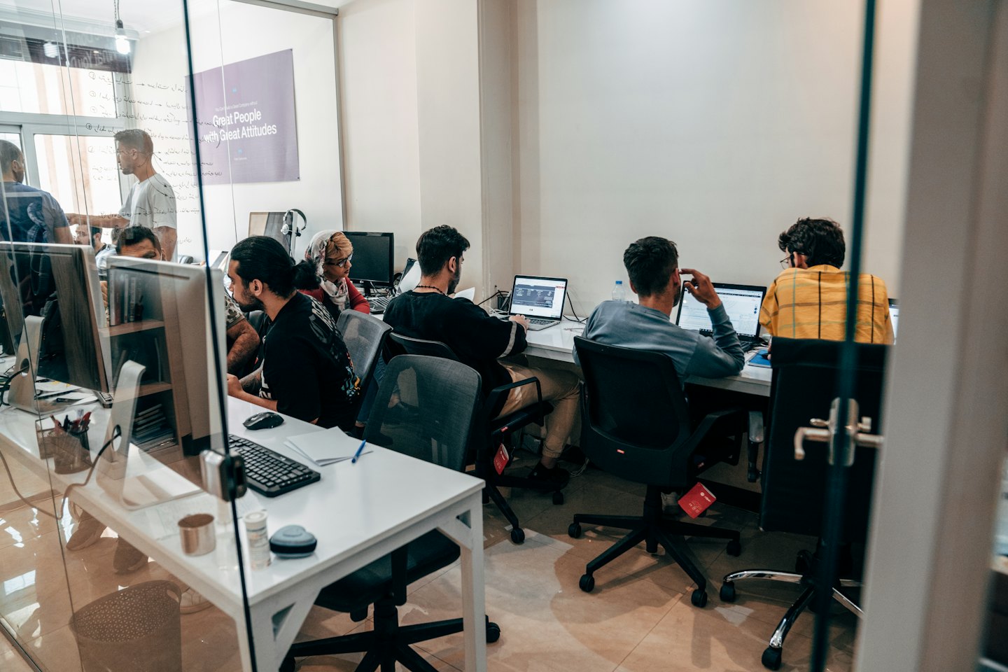 Junge Erwachsene arbeiten gemeinsam an Laptops in einem modernen Büro.